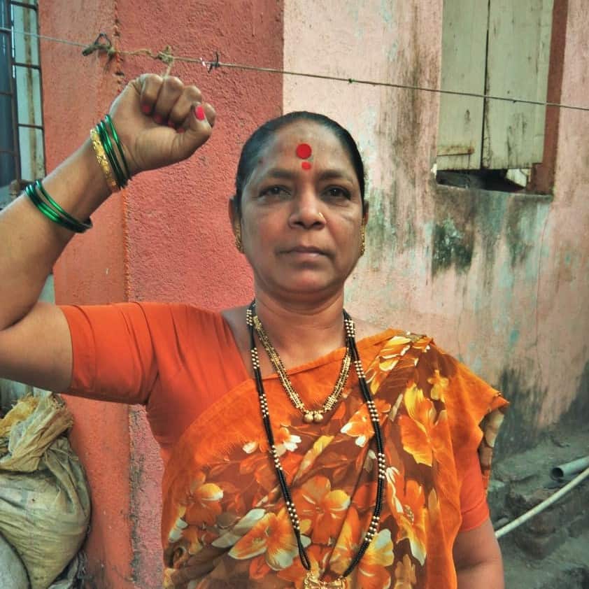 Sunita faces the camera with her fist raised