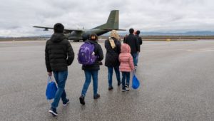 Afghan refugees walk to a departing plane