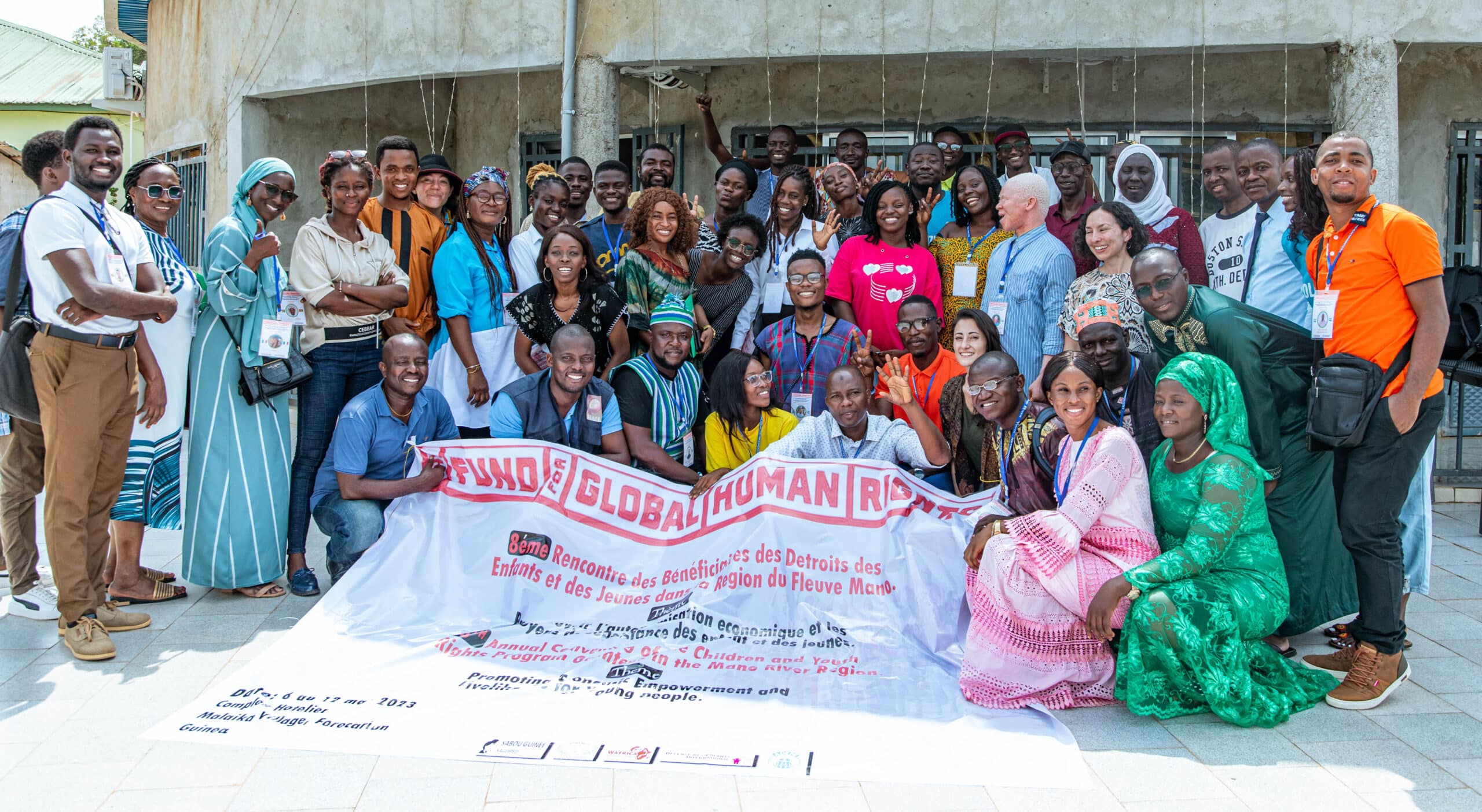 Youth activists from Liberia, Guinea, Cote d'Ivoire, and Sierra Leone gather around a banner celebrating the convening.