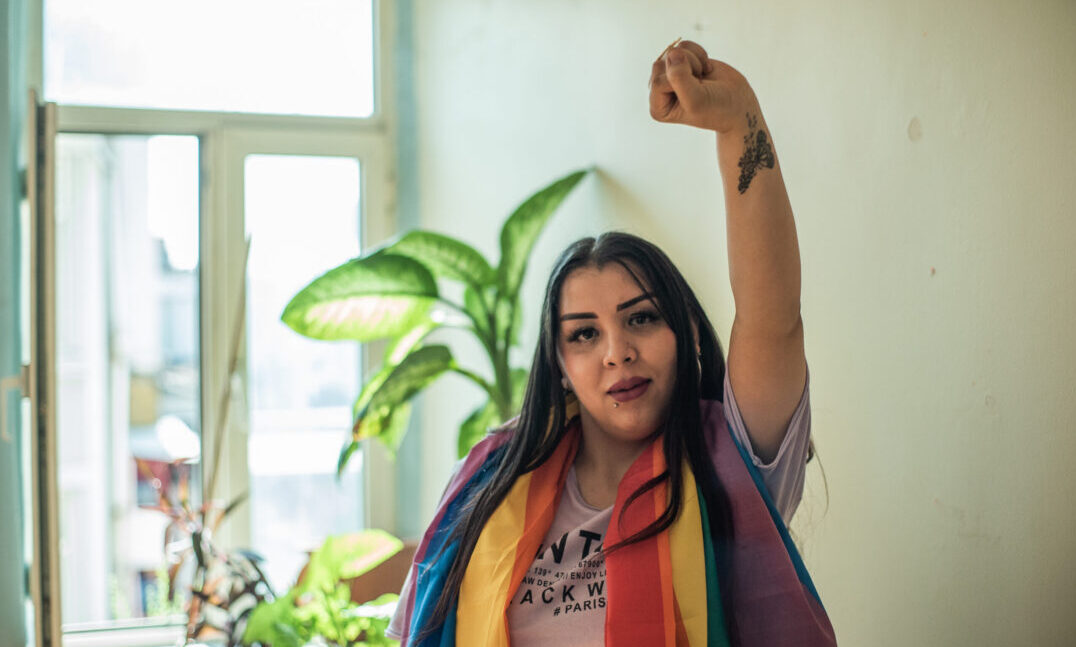 DSC00553 A Fund grantee from the Aman Project in Turkey wears an LGBTQ pride flag and has a raised fist.