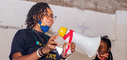 A Fund grantee from Girls Behind the Lens in Sierra Leone stands with a microphone